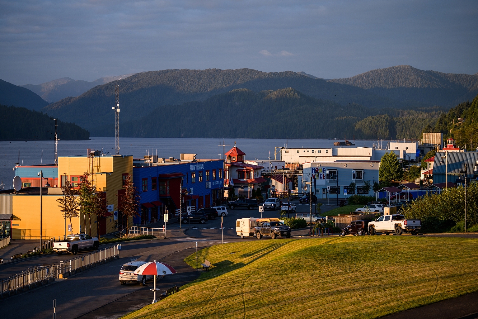 The sun sets over Cow Bay, a small town on the oceanfront. Mountains are in the distance.