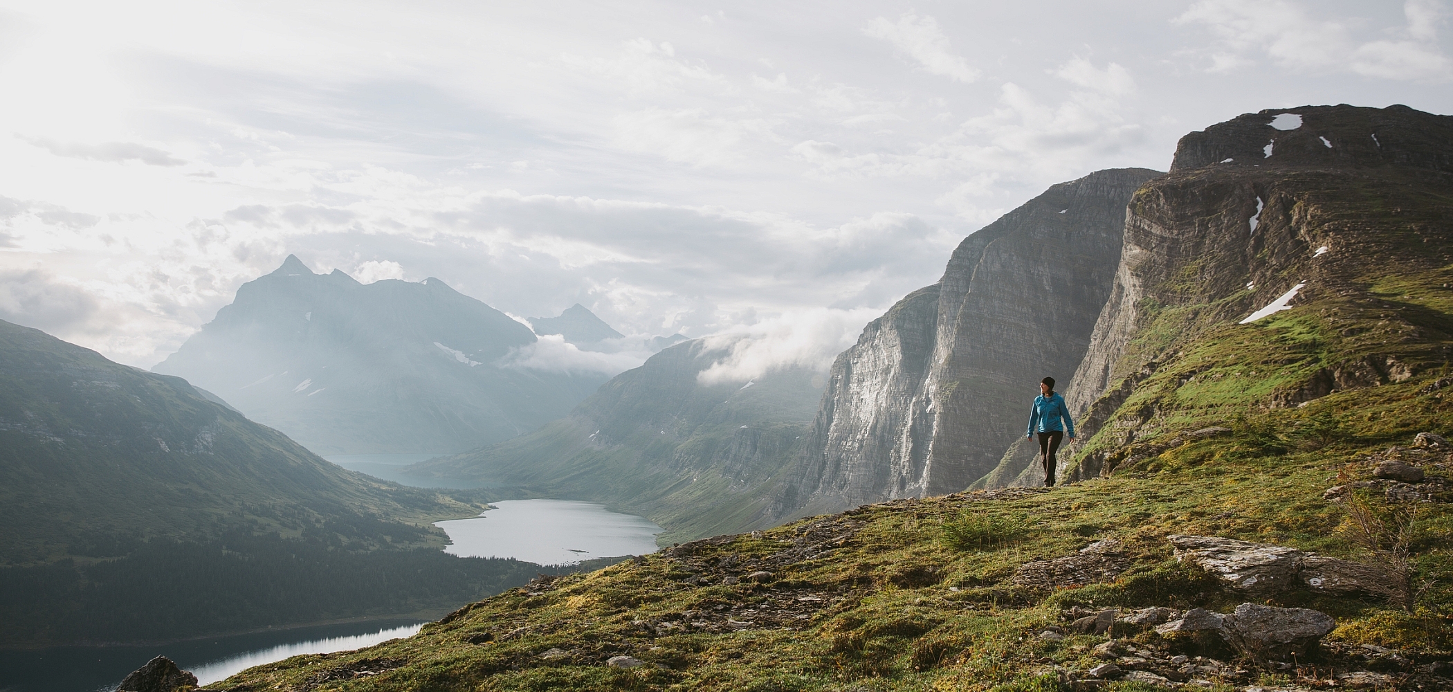 A hiker surrounded by towering mountains and alpine lakes.