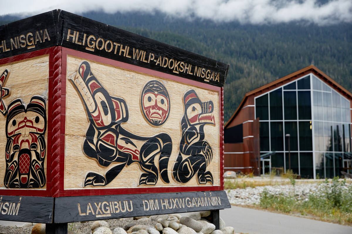 A sign with Nisga'a artwork leads to a beautiful wooden building with floor to ceiling windows looks out over the Nisga'a Lava Beds Provincial Park.