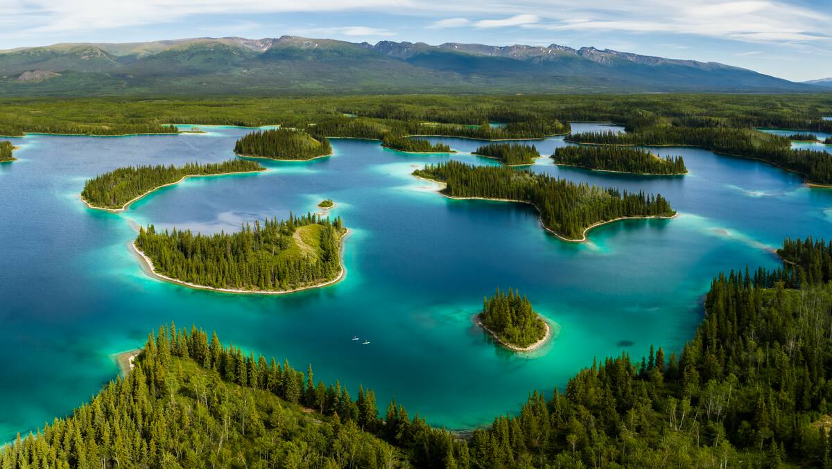 Paddlers glide through a turquoise lake dotted by treed islands.